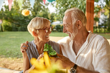 Glückliches älteres Paar stößt bei einer Gartenparty mit Bierflaschen an - ZEDF01639