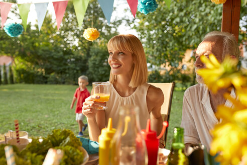 Lächelnde Frau trinkt Orangensaft auf einer Gartenparty - ZEDF01641