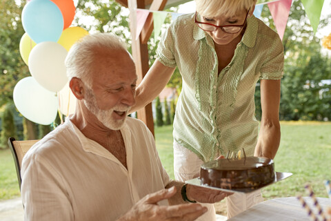 Frau übergibt Kuchen an glücklichen Ehemann auf einer Gartenparty, lizenzfreies Stockfoto