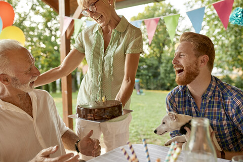 Glückliche Frau bei der Übergabe einer Torte auf einer Gartenparty, lizenzfreies Stockfoto