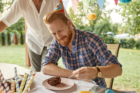 Mann isst Kuchen auf einer Geburtstagsparty im Garten - ZEDF01677