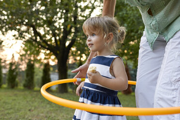 Grandmother and granddaughter playing together in garden with hoola hoop - ZEDF01683