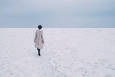 Frau in Mantel und Hut geht in verschneiter Landschaft spazieren - FSIF03178