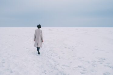 Woman in coat and hat walking in snow covered landscape - FSIF03178