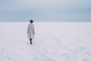 Woman in coat and hat walking in snow covered landscape - FSIF03178