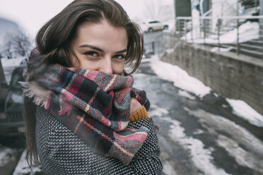 Portrait confident young woman in plaid scarf on snowy winter street - FSIF03179