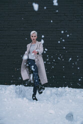 Portrait young woman kicking snow - FSIF03181