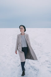 Woman in coat and hat walking in snow covered landscape - FSIF03182