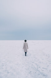 Woman in coat and hat walking in snow covered landscape - FSIF03184