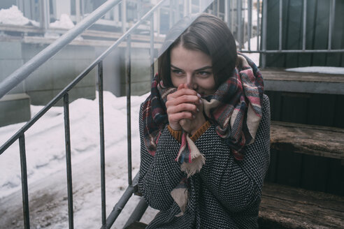 Junge Frau wärmt sich die Hände auf einer kalten, winterlichen Treppe - FSIF03185