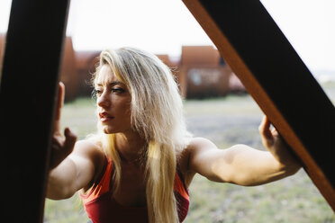 Athletic woman doing stretching exercise at industrial site - FMGF00060