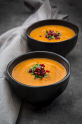 Bowl of carrot ginger coconut soup with topping of parsley and pomegranate seed - LVF07454