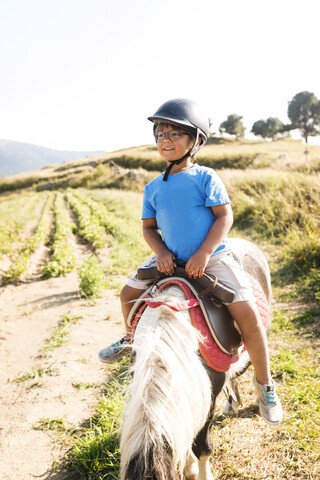 Spanien, Cerdanya, Porträt eines kleinen Jungen, der auf einem Pony reitet, lizenzfreies Stockfoto