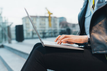 Businesswoman, sitting outdoors, using laptop, mid section - CUF45198