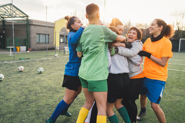 Football players jubilant and hugging on pitch - CUF45227