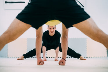 View through mans legs of friends doing stretching exercise - CUF45259