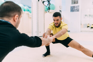 Männer im Fitnessstudio bei Dehnungsübungen - CUF45260