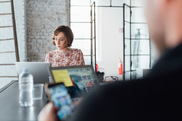 Colleagues in office using laptops and smartphone - CUF45279