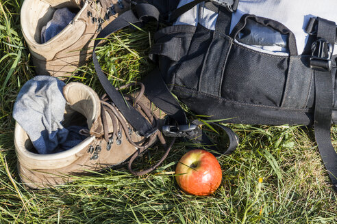 Wanderschuhe, Rucksack und Apfel auf einer Wiese - TCF05845