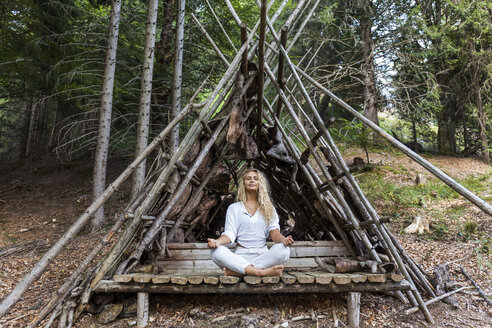 Junge Frau macht Yoga in einem Schutzraum im Wald - TCF05855