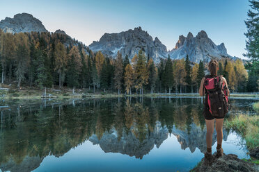 Hiker by lake looking at mountain ranges, Dolomites, Cortina d'Ampezzo, Veneto, Italy - CUF45526