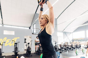 Frau beim Gewichtheben mit Kesselglocke im Fitnessstudio - CUF45570
