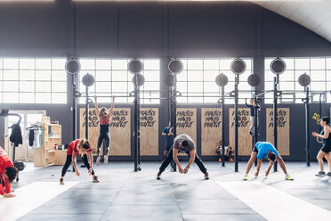 Gruppe von Menschen, die in einem Fitnessstudio trainieren und sich nach vorne beugen - CUF45579