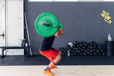 Seitenansicht eines Mannes, der eine Langhantel im Fitnessstudio hebt - CUF45605