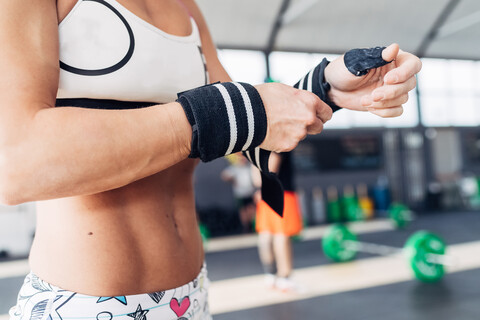 Ausschnitt einer Frau, die sich auf das Gewichtheben vorbereitet und Turnhandschuhe trägt, lizenzfreies Stockfoto