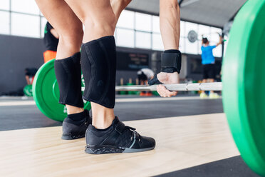 Cropped view of woman weightlifting barbell in gym - CUF45607