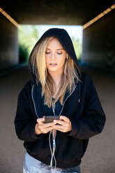 Young woman listening to music on mobile phone in tunnel - CUF45647