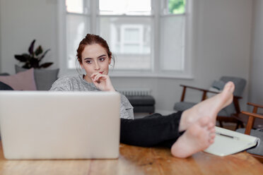 Woman using laptop on dining table - CUF45683