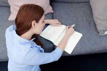 Woman sitting on floor writing in notepad - CUF45690