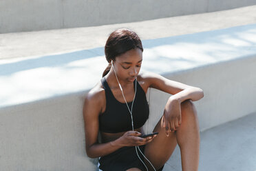 Junge Frau hört Musik auf einem Mobiltelefon - CUF45808