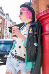 Junge Frau mit rosa Haaren und schrulligem Stil lehnt an einem roten Briefkasten, London, UK - CUF45816