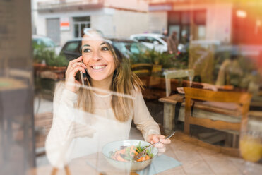 Woman using mobile while having vegan meal in restaurant - CUF45866