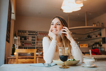 Frau benutzt ihr Handy, während sie in einem Restaurant vegan isst - CUF45869