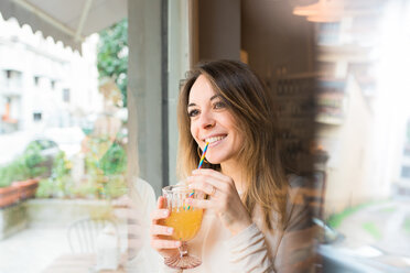 Woman having drink by window in restaurant - CUF45874