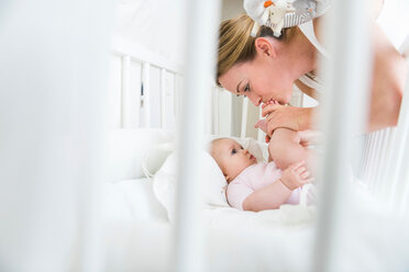Mother kissing baby's feet in cot - CUF45887