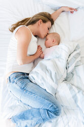 Mutter küsst schlafendes Baby im Bett - CUF45888