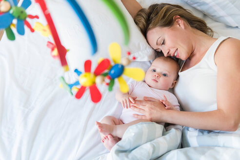 Mother and baby in bed, looking at crib carousel - CUF45890