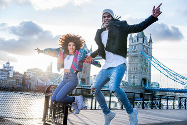 Junges Paar im Freien, das vor Freude springt, Tower Bridge im Hintergrund, London, England, UK - CUF45911
