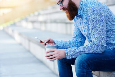 Bearded man sitting on step using smartphone - CUF45943