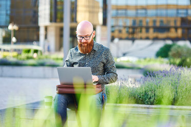 Bearded man using laptop outdoors - CUF45949