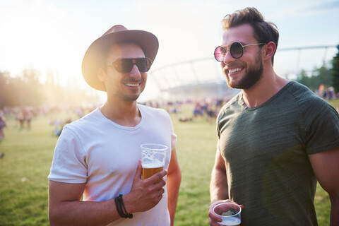 Zwei junge männliche Freunde mit Biergläsern beim Holi-Festival, lizenzfreies Stockfoto