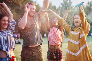 Vier junge erwachsene Freunde tanzen und werfen farbiges Kreidepulver beim Holi-Festival - CUF45960