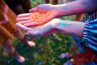 Young woman with cupped hands holding coloured chalk powder at Holi Festival, close up of hands - CUF45961