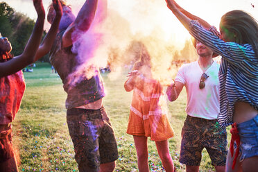 Fünf junge erwachsene Freunde tanzen und werfen farbiges Kreidepulver beim Holi-Festival - CUF45962