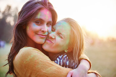 Zwei junge Frauen, deren Gesichter mit farbigem Kreidepulver bedeckt sind, umarmen sich beim Holi-Festival, Porträt - CUF45969