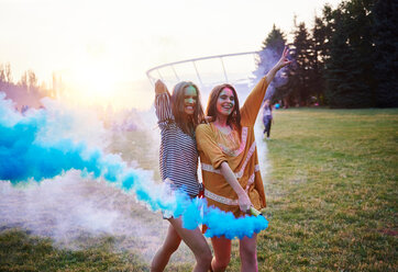 Two young women dancing with blue smoke bombs at Holi Festival - CUF45971